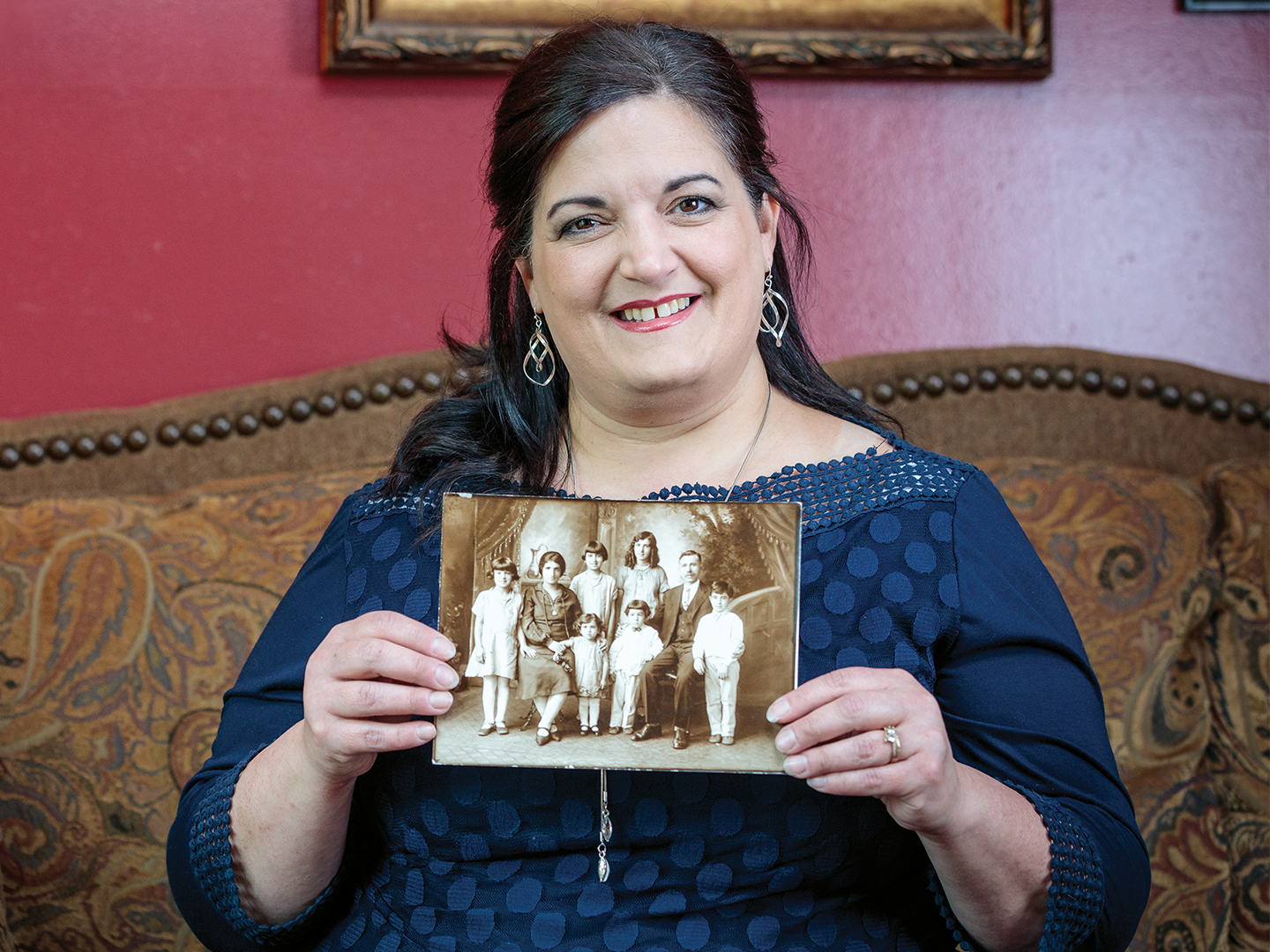 A woman in blue dress holding a vintage family photo.