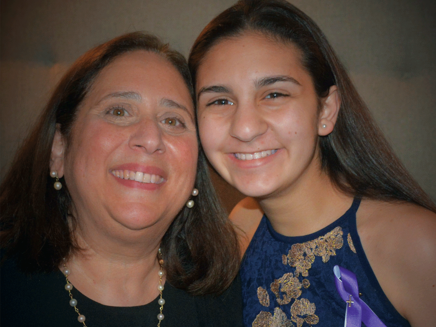 Female attorney poses with her daughter. Both are smiling.