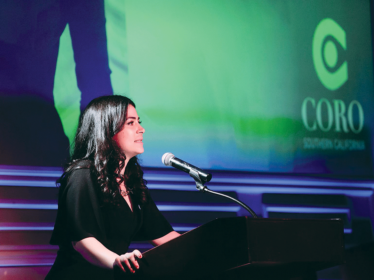 A woman speaks to an audience in a Gala