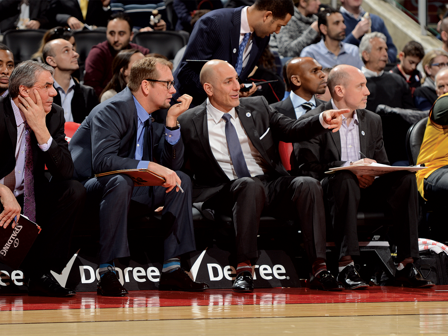 Rex Kalamian sits courtside with other members of the Raptors coaching staff.