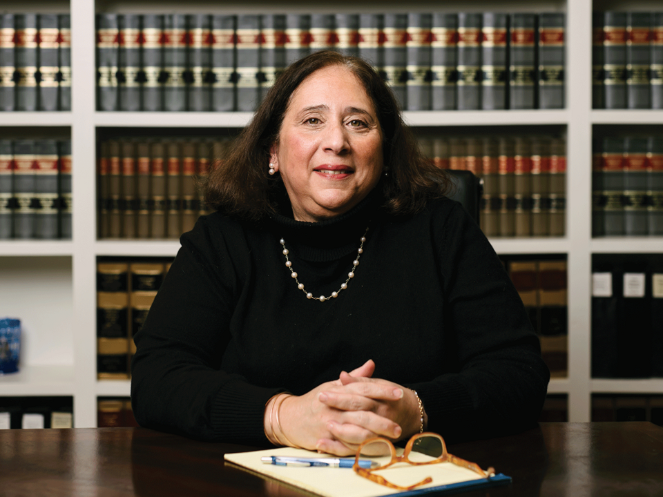 Female attorney in her office, sitting with law books behind her