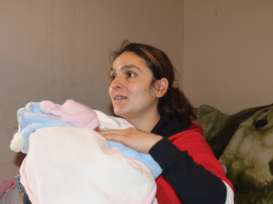 A new mother, recently displaced from Qelbajar, cradles her newborn in temporary housing in Garni.