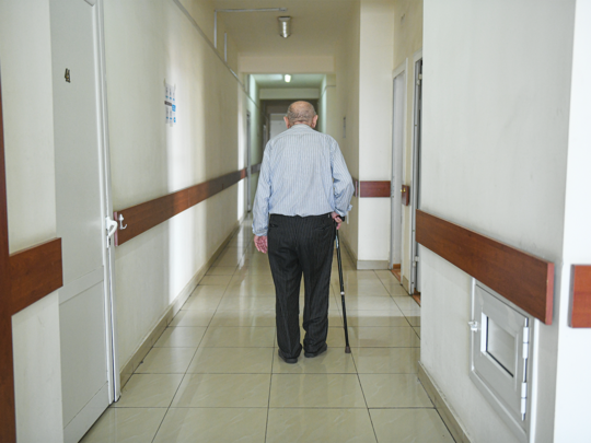 Older man walking down the hallway of a senior care center.