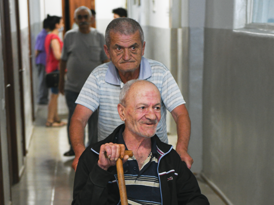 Andranik, 69, gets helped by a fellow Narek Nursing Home patient.