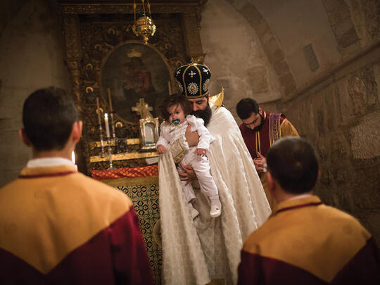 One-year-old Njteh Sevan is held by a priest during his christening ceremony at the Archangels Church.