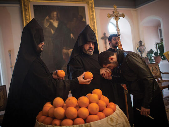 An Armenian seminary student receives a blessed orange from the Patriarch, a blessing symbolic for the New Year.