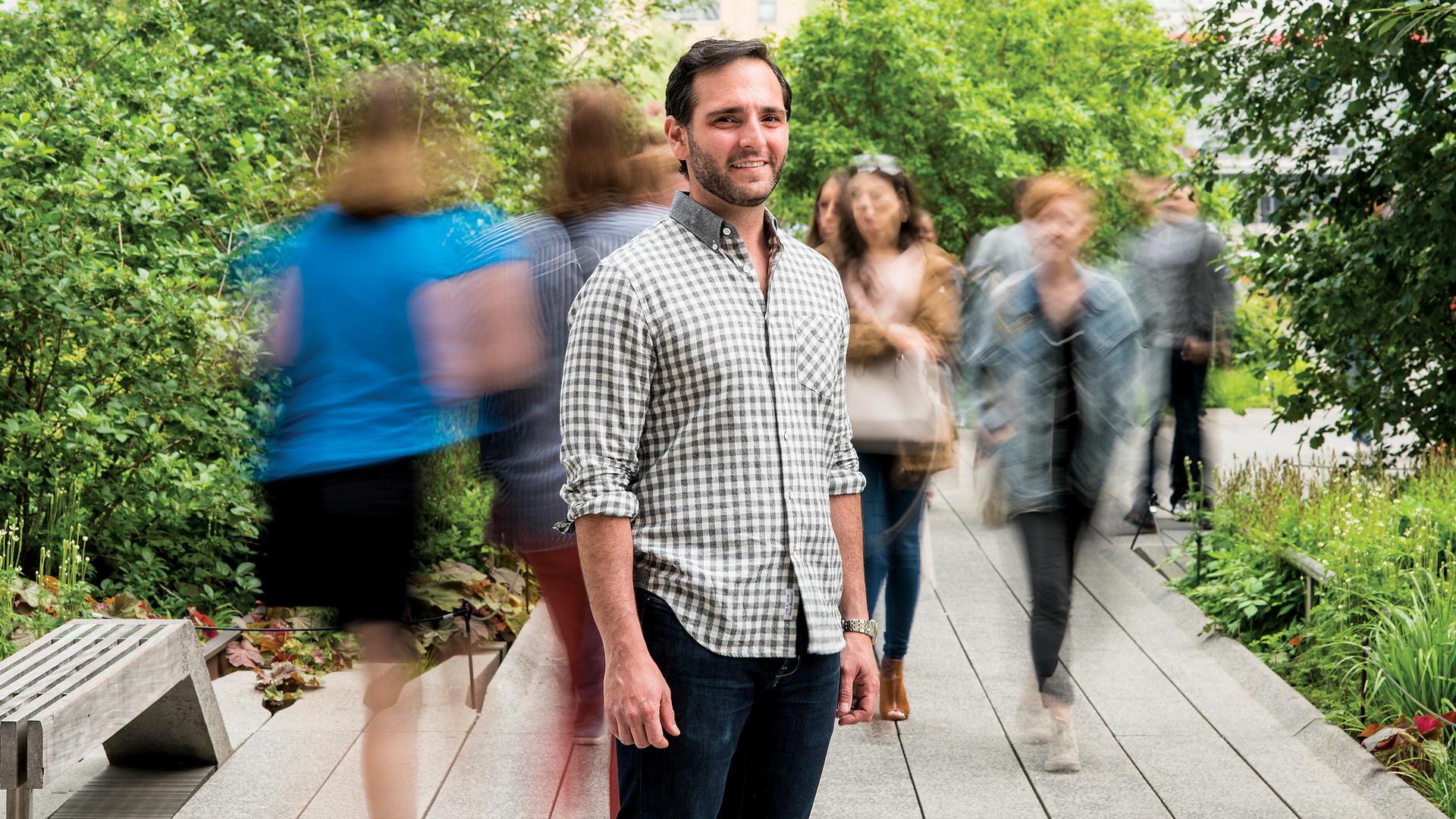 Smiling Young man in front of blurred walking people