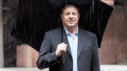 A man in a suit and an umbrella standing under the rain