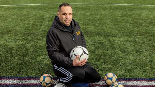 Coach David Dikranian sitting in the center of a soccer field